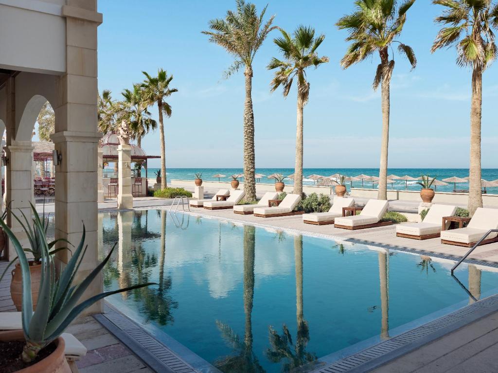 Grecotel Plaza Beach House pool lined with palm trees by the sea