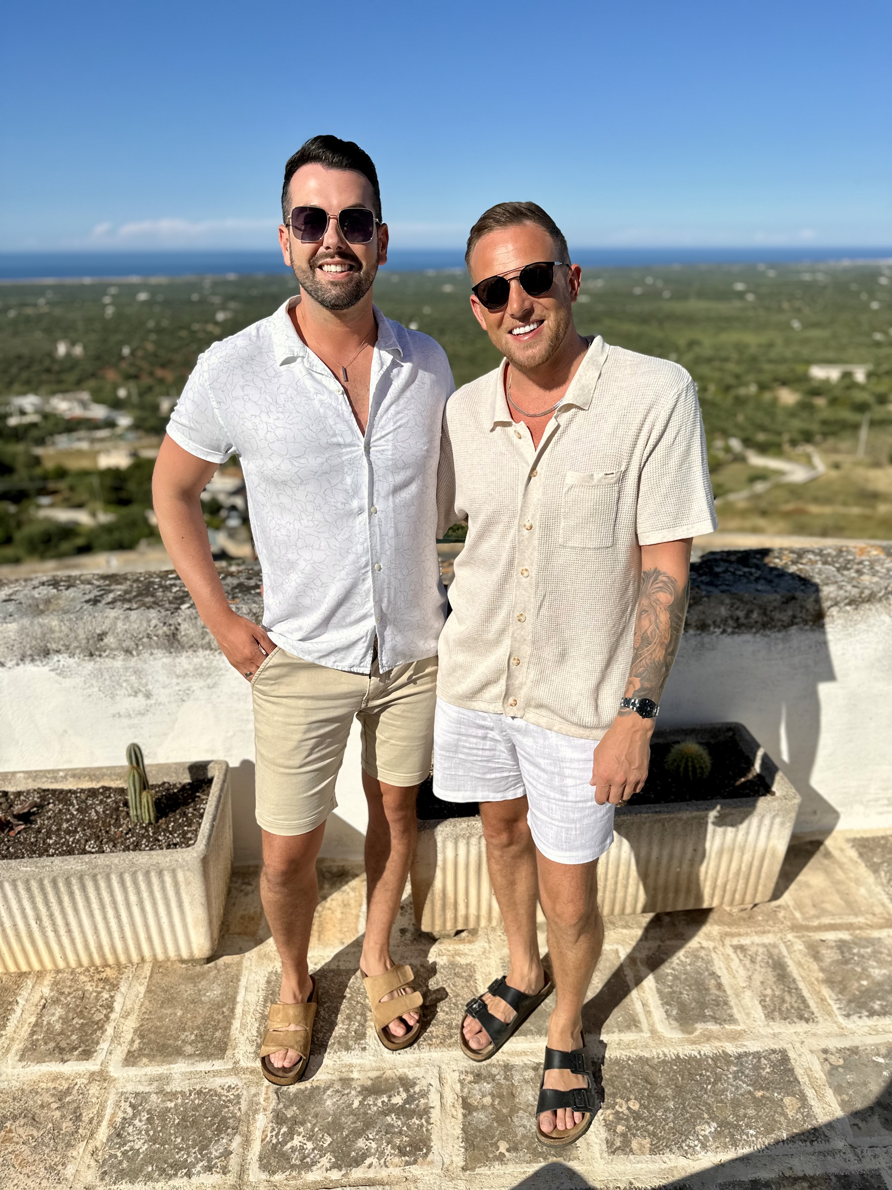 Mark and Mikey on a sunny rooftop terrace in Puglia with countryside behind